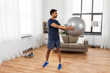 健身、运动和健康的生活方式理念--印度男子在家中带球锻炼。印度男子在家中带着健身球锻炼