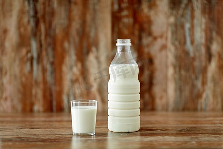 食品和奶制品概念—玻璃和牛奶瓶在木桌上。玻璃和一瓶牛奶在木桌上