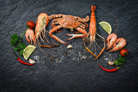 贝类海鲜板与虾蟹海洋美食晚餐海鲜烹调与草药和香料在黑暗背景 