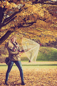 放松的概念。妇女走在公园与伞，秋天明亮的天气。妇女走在公园与伞