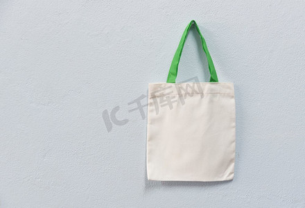 白色手提袋帆布织物生态袋布购物袋在墙背景/零废物使用较少的塑料说没有塑料袋污染问题概念