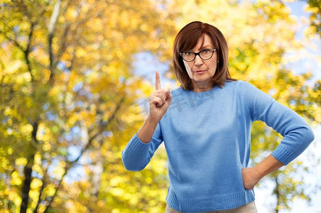 情绪和老人概念—不愉快的高级妇女眼镜警告在秋天公园背景不高兴的高级妇女眼镜警告