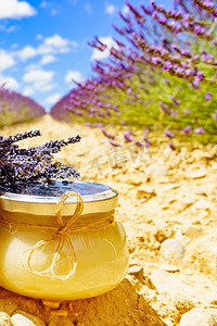 熏衣草摄影照片_与蜂蜜的罐对新鲜熏衣草领域背景。法国普罗旺斯一罐蜂蜜和熏衣草花。