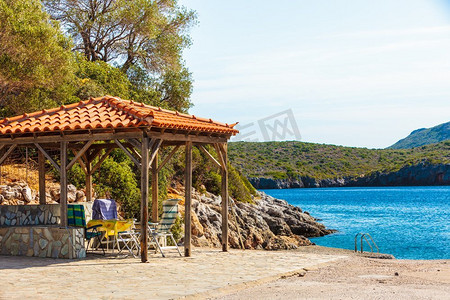 希腊海滩上田园诗般的放松之地。没有人在木屋顶下的躺椅。空的希腊海滩与放松停止