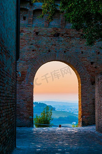 marche摄影照片_柔和的日落通过中世纪城镇格拉达拉在意大利的拱门看到