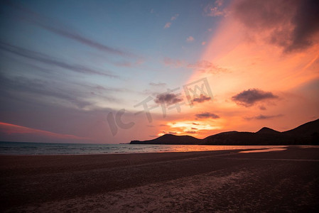 海滩夕阳剪影海岛美丽的海滩沙滩上的沙滩夏日五颜六色的橙色和蓝色的天空，山脉的背景