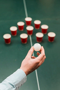 人手拿着白色球玩啤酒乒乓游戏