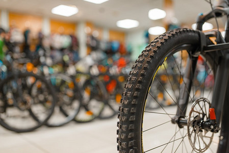 山地自行车摄影照片_运动商店里的山地自行车，专注于前轮，没有人。暑期活动休闲，展示自行车，自行车销售，专业自行车装备