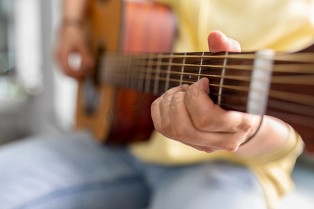 弹窗摄影照片_休闲、音乐和人的概念-男人坐在窗台上弹吉他的特写。男人坐在窗台上弹吉他的特写