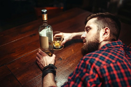 喝醉的男人睡在吧台，俯视，酗酒成瘾。酒吧里的男性，酗酒。醉酒男子睡在酒吧柜台，俯视
