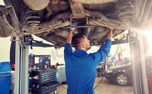 汽车维修，维修，保养和人员概念—汽车修理工或铁匠在车间工作。在车间修理汽车的机修工或铁匠
