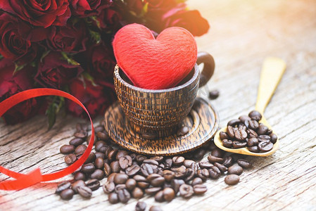 咖啡豆红色摄影照片_心在木咖啡杯与咖啡豆浪漫爱情情人节和红玫瑰花在木背景/爱咖啡概念