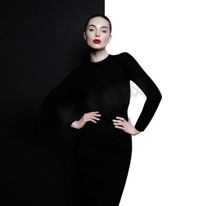 时尚艺术工作室几何黑白背景下的优雅女性肖像。专业化妆，涂上红色口红。时尚的经典连衣裙。