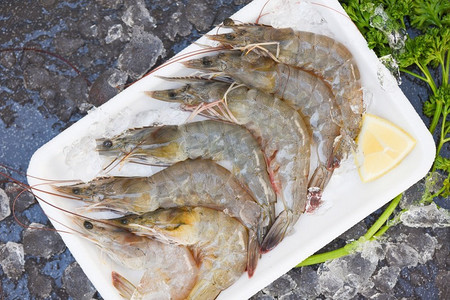 新鲜的虾虾用香料在黑暗背景的柠檬在海鲜餐馆，生虾在板塑料托盘，顶视图