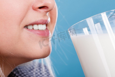 健康的饮料，良好的营养，完美的早餐理念。女人从玻璃杯里喝牛奶。妇女喝牛奶从玻璃