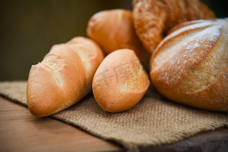 各种面包和小圆面包/新鲜烘焙面包各种类型的袋装在乡村餐桌上自制早餐食品概念