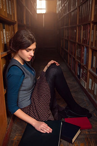 大学生坐在图书馆的地板上，放着摊开的书和课本。