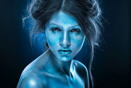 幻想的女人与蓝色霜化妆和皮肤。冰皇后人体艺术荧光化妆品
