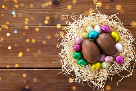 复活节，糖果和假日概念—巧克力蛋和糖果在稻草巢在木背景巧克力蛋和巧克力糖果在稻草巢