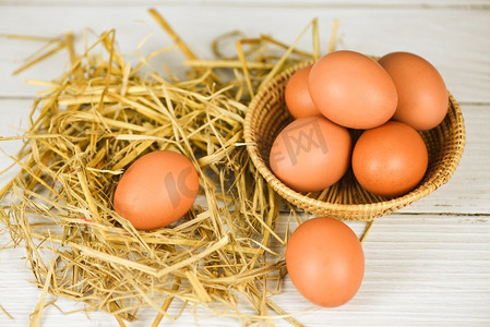 新鲜的鸡蛋在篮子和稻草有木桌背景顶视图/生鸡蛋收集从农产品自然鸡蛋