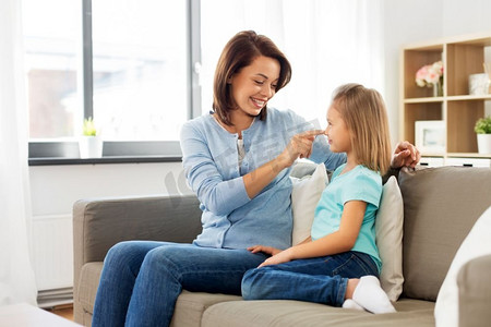 家庭，世代和人的概念—快乐微笑的母亲和女儿看着对方在家里。母亲和女儿坐在沙发上在家里