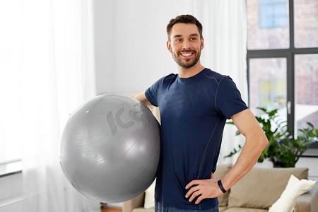 健身，运动和健康的生活方式概念—男子在家里用球锻炼。男子在家里用健身球锻炼
