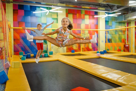 游戏室摄影照片_小女孩和男孩有乐趣在儿童蹦床，游乐场在娱乐中心。室内儿童游戏区，游戏室
