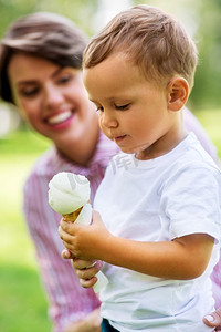 家庭，休闲和人的概念—小男孩在夏天和妈妈吃冰淇淋。夏天和妈妈一起吃冰淇淋的小男孩