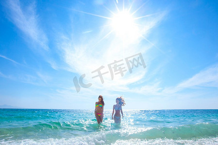 热带海摄影照片_美丽的适合妇女在比基尼运行从热带海海滩。穿着比基尼的女人跑到海滩