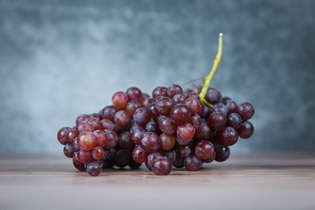 在木桌的红葡萄/束葡萄多汁的水果在光和黑暗背景