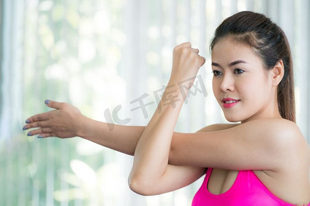 运动妇女做手臂伸展，在室内健身房热身。健康的生活方式和健康理念。