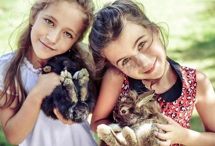 两个欢快的女孩拥抱毛茸茸的兔子