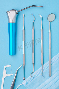 在浅蓝色背景顶视图平躺牙医工具。牙齿护理，牙齿卫生和健康概念。 