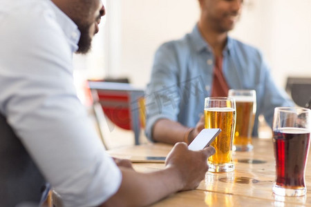 人和技术概念—人与智能手机喝啤酒和阅读消息在酒吧或酒馆。男子与智能手机喝啤酒在酒吧或酒馆