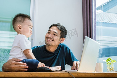 电脑主题摄影照片_单身父子快乐地在一起使用笔记本电脑。科技和生活方式的概念。幸福的家庭和婴儿主题。