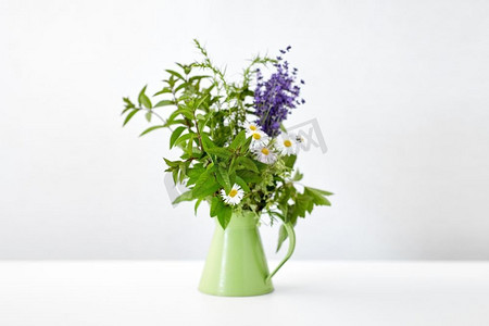 园艺，植物和有机概念—一束草药和鲜花在绿色壶在桌子上。一束草药和鲜花在绿色壶在桌子上