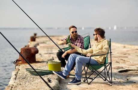 消闲与人的概念—夏日，朋友在码头钓鱼、喝啤酒。快乐的朋友钓鱼和喝啤酒在码头