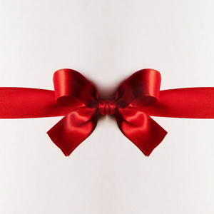 蝴蝶结礼物摄影照片_红色礼物缎子蝴蝶结在白色背景。红色礼品蝴蝶结白色