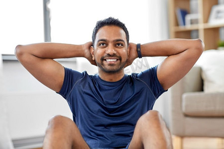 运动、健身和健康的生活方式概念—微笑的印度男子在家里做腹部练习。印度男子在家里做腹部练习