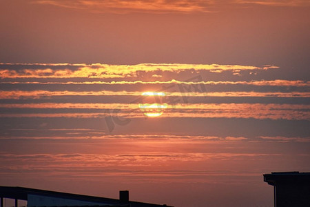 红色日落在屋顶剪影在傍晚与云覆盖太阳