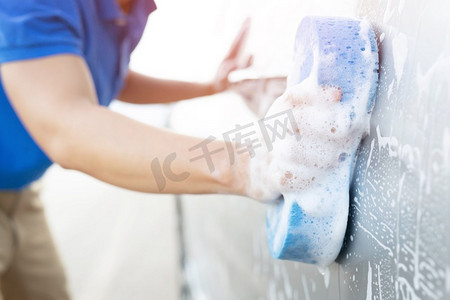 洗车请左转谢谢摄影照片_人们手握蓝色海绵洗车。	