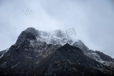 令人惊叹的喜怒无常的戏剧性冬季风景斯诺多尼亚的Y Garn白雪皑皑，鸟儿在高空飞翔