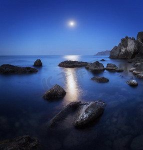 五颜六色的夜晚景观与满月，月球路径和岩石在夏天。在海上的山脉景观
