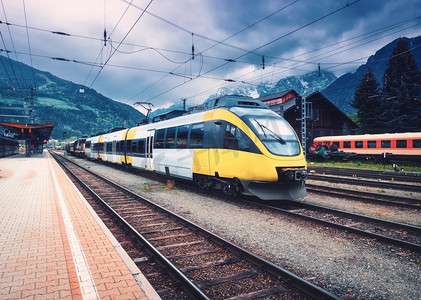 美丽的高速列车在山区火车站在秋天日落时在铁路站台上的黄色现代通勤