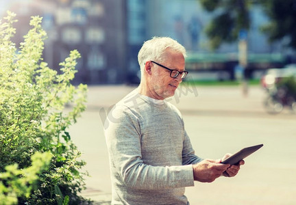 科技、人和生活方式理念--城市街道上使用平板电脑的老年人。城市街道上拿着平板电脑的老人