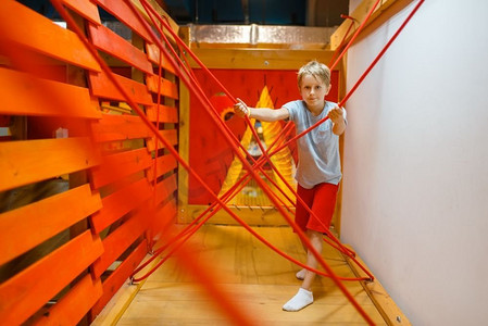 小男孩玩绳迷宫，游乐场在娱乐中心。室内游戏区，游戏室