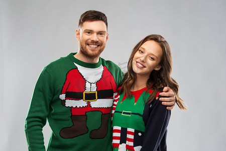 圣诞节，人和节日的概念-丑陋毛衣派对上幸福的情侣肖像。圣诞丑陋毛衣派对上的幸福情侣