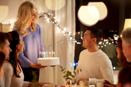 正在燃烧的蜡烛摄影照片_庆祝和人的概念-快乐的家庭蛋糕在家里举行生日派对。幸福的一家人吃蛋糕办生日派对