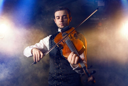 在小提琴上演奏古典音乐的男小提琴家，小提琴手在舞台上的行动