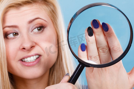 竖纹长虹玻璃摄影照片_凝胶混合美甲概念。金发女人看着她的蓝色画长美丽的指甲。女人看指甲通过放大镜